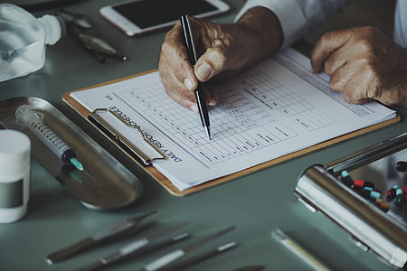 person holding ballpen while writing on paper thumbnail