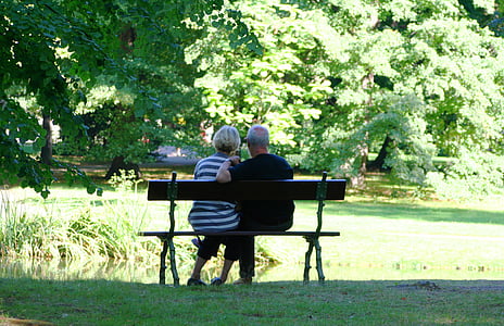 man and woman sitting on the bench surrounded with trees thumbnail