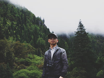 man standing near trees on hill thumbnail