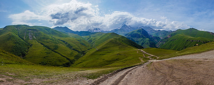 pathway leading to green hill under white clouds and blue sky thumbnail