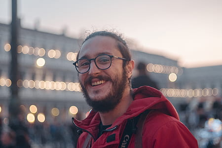 selective focus photography of smiling man wearing red zip-up hoodie thumbnail