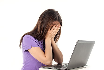 woman in purple top sitting in front of gray laptop computer thumbnail