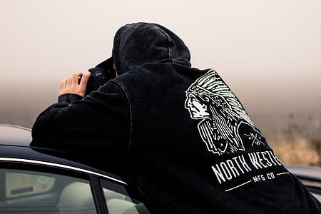 man leaning on car hood while taking picture thumbnail