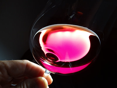 person holding wine glass with pink liquid inside thumbnail
