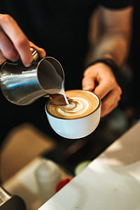 person pouring milk on white ceramic mug thumbnail