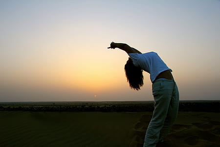 woman wearing white crew-neck shirt standing on the field during golden hour thumbnail