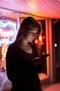 woman in red V-neck shirt holding smartphone thumbnail