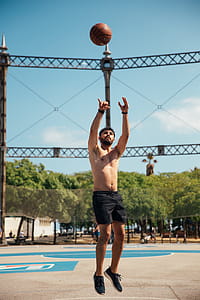A young man in black shorts shooting a basketball in an outdoor basketball court thumbnail