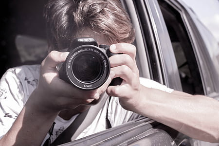 person holding DSLR camera inside car during daytime thumbnail