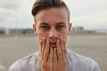 man wearing gray crew-neck shirt touching his face thumbnail