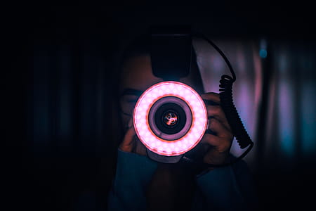 Person Holding Camera With Red Lights on Lens thumbnail