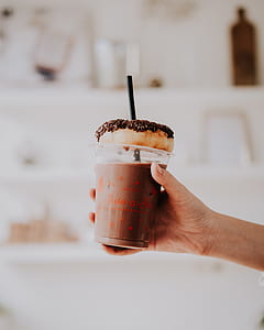 person holding cup with doughnut on top thumbnail