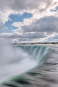 photo of waterfalls under cloudy sky at daytime thumbnail