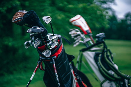 golf clubs in golf bags on grass field thumbnail