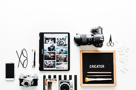black tablet computer beside DSLR camera and SLR camera thumbnail
