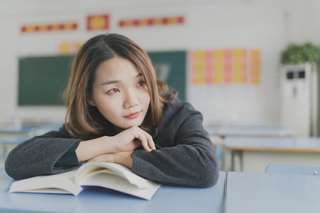 selective focus photography of woman wearing black sweater leaning by the book thumbnail