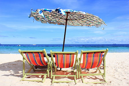 patio umbrella and three beach chairs on seashore thumbnail