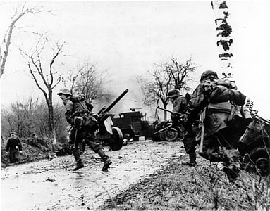 German troops advancing past abandoned American equipment during the Battle of the Bulge thumbnail