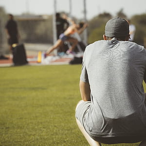 man in gray T-shirt crouching and watching on woman running on field thumbnail