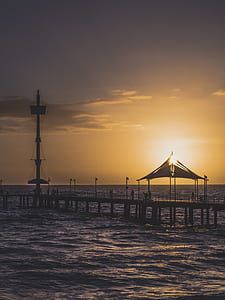 person standing on brown wooden dock during golden hour thumbnail