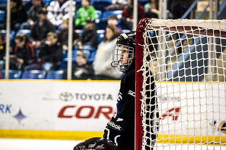 Ice Hockey player holding white and red goalie net thumbnail