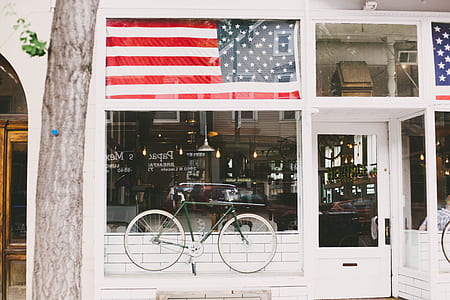 green commuter bike on top of white wooden board infront of clear glass wall thumbnail