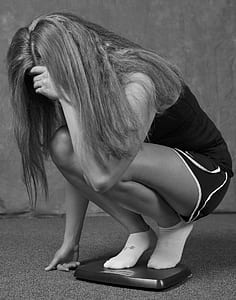 grayscale photography of woman standing on bathroom scale thumbnail