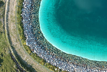 aerial view of teal body of water surrounded with pebble stone thumbnail