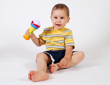 toddler boy holding rattle toy sitting on floor thumbnail