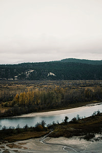 body of water surrounded by trees and mountains thumbnail