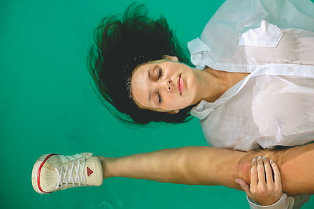 woman in white shirt floating on water while holding human leg thumbnail