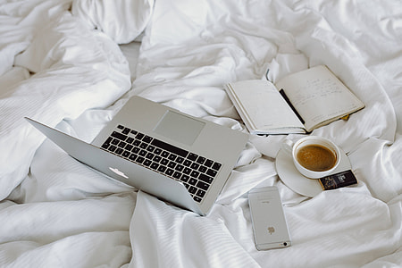 Woman working on a laptop while enjoying a breakfast coffee and chocolate in bed thumbnail