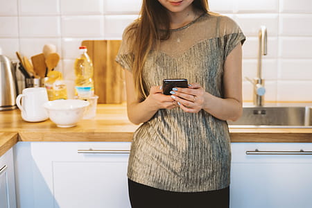 Woman texting with smart phone in kitchen thumbnail