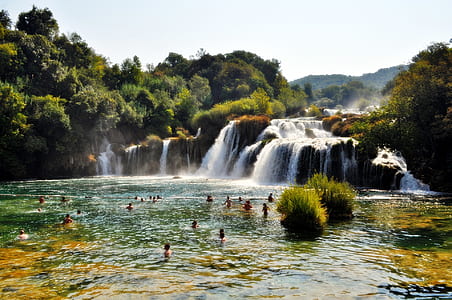 People Swimming Near Waterfall during Daytime thumbnail