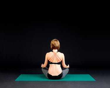 woman in black sports bra sitting on green yoga mat thumbnail