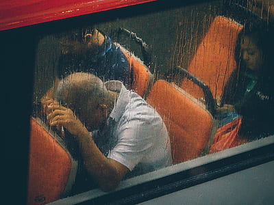 man in white collared t-shirt sitting on orange leather vehicle seat beside man in blue shirt using phone thumbnail