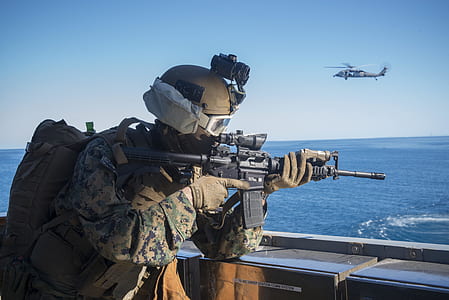 man carrying black M4A1 carbine near gray helicopter thumbnail