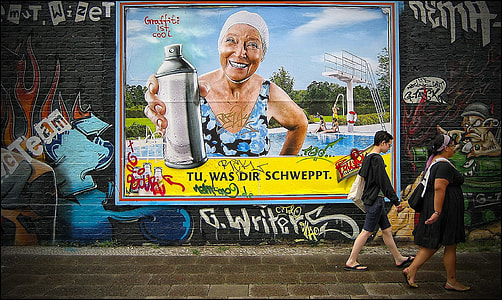 boy and woman walking beside wall with graffiti thumbnail