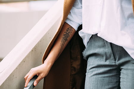 person's hand with tattoo on wrist touching the gray balustrade thumbnail
