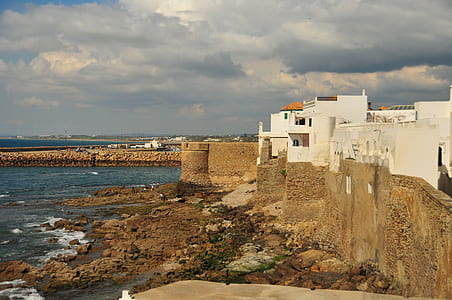 white concrete buildings by shore under white sky at daytime thumbnail