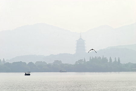 pagoda temple on mountain across body of water with bird flying near boat thumbnail