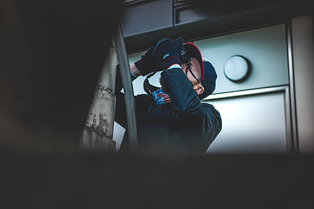 man holding black camera pointing upwards near wall thumbnail