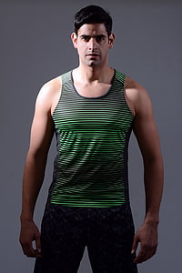 man wearing black and green striped tank top and gray bottoms standing thumbnail