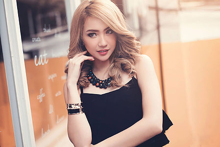 photo of woman with black spaghetti strap top holding cheek thumbnail