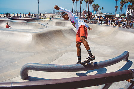 man wearing white long-sleeved shirt ride-on skateboard grinding on rail photography thumbnail