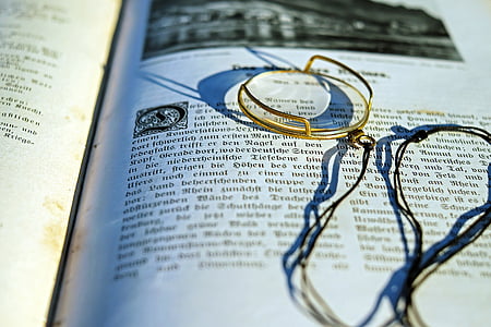 gold-colored framed eyeglass on top of book thumbnail