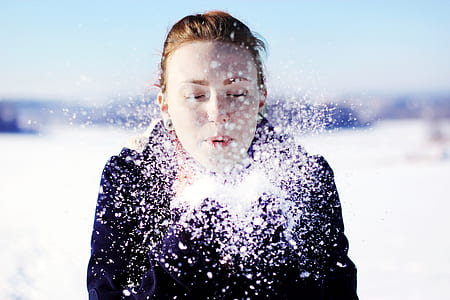woman blowing snow powder taken during daytime thumbnail