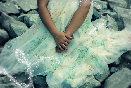 person wearing white floral gown sitting on boulders thumbnail