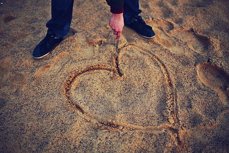 person drawing heart on sand thumbnail