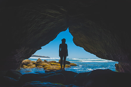 silhouette of woman standing on rock beside ocean thumbnail